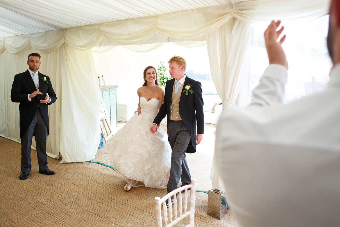 bride and groom walk into the marquee