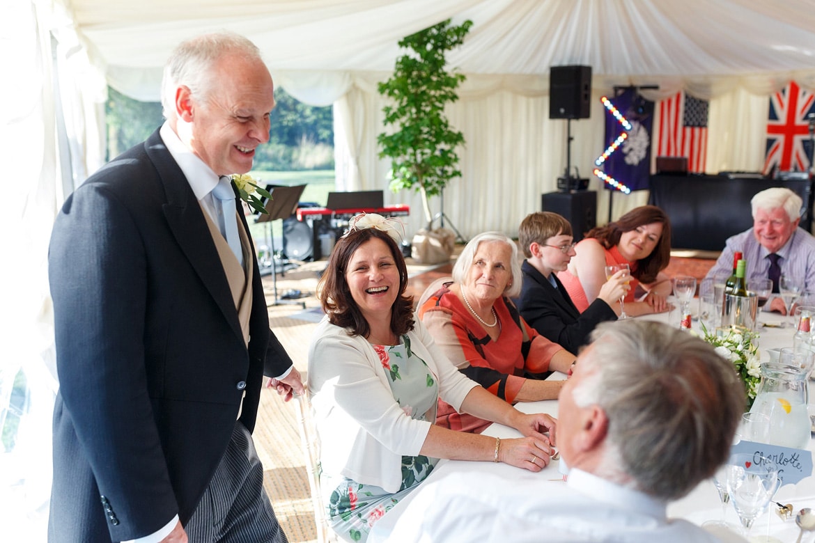 the grooms father laughs with the wedding guests