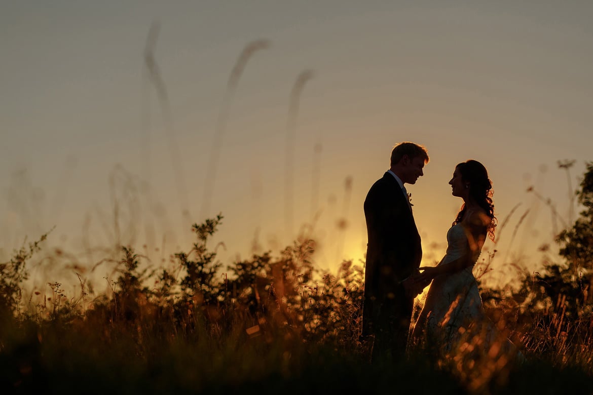 a bride a groom silhouette against a suffolk summer sunset