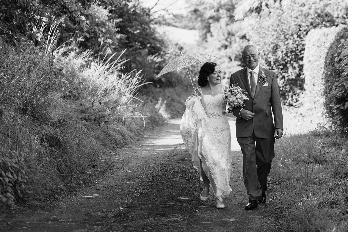 the bride and father walk down the lane to the ceremony