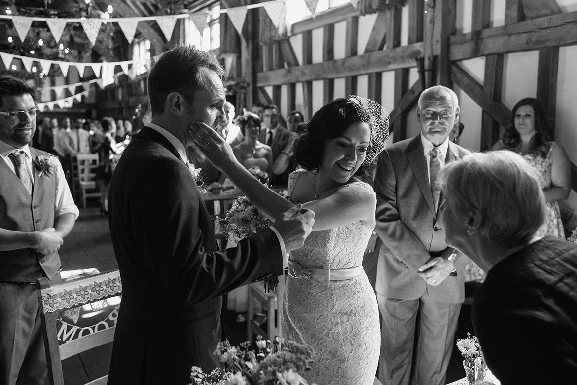 a bride wipes a tear from the grooms face