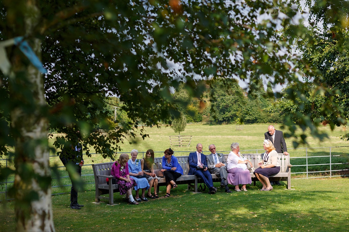 wedding guests seated in the shade of the trees