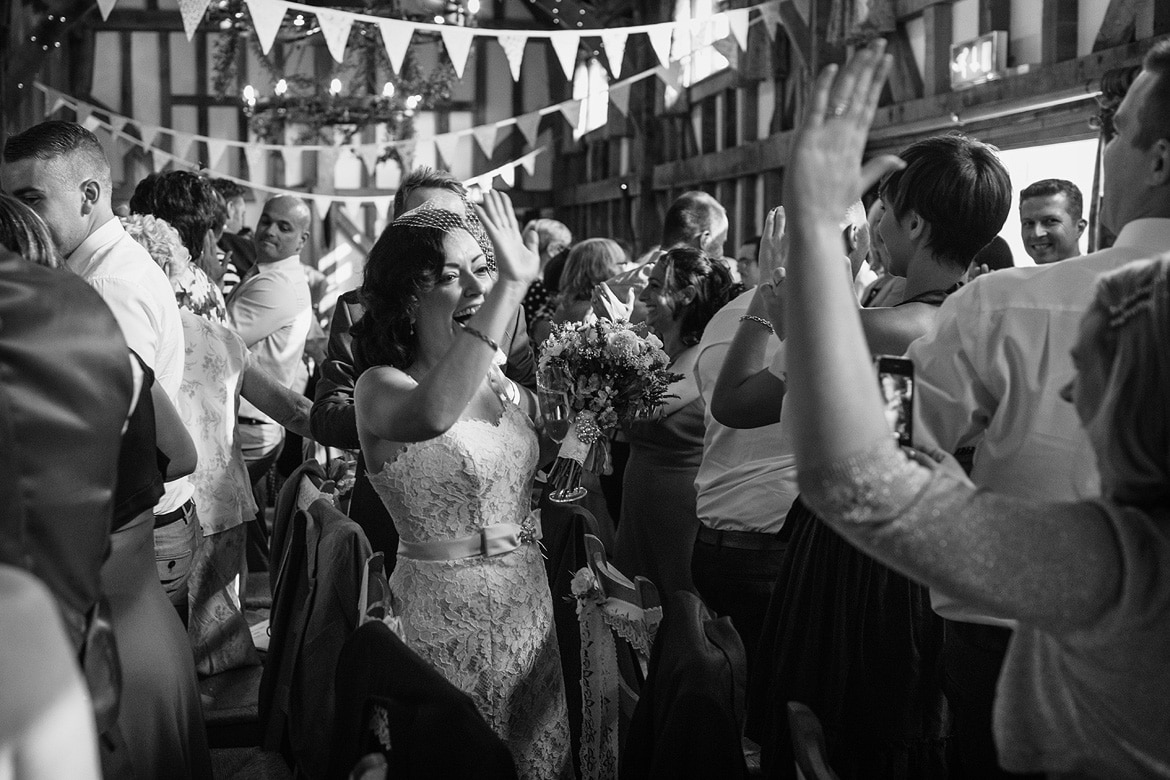 the bride high fives a guest as she enters the wedding breakfast at gate street barn