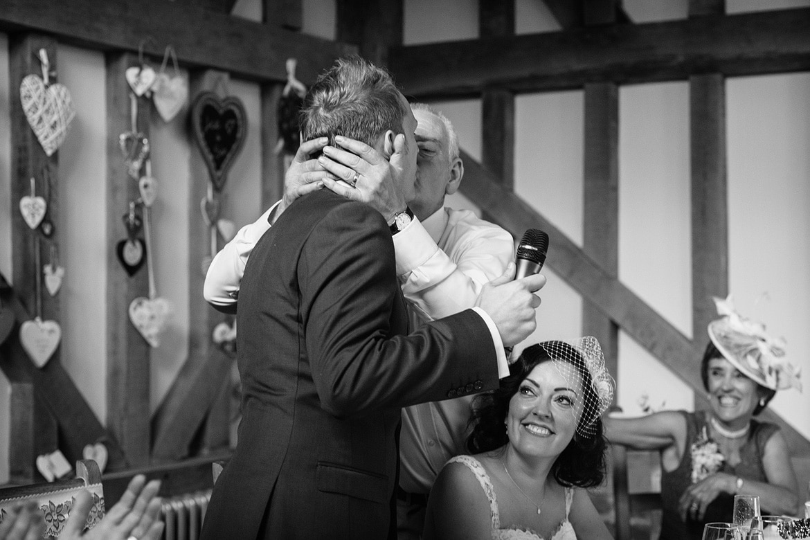 the father of the bride kisses the groom