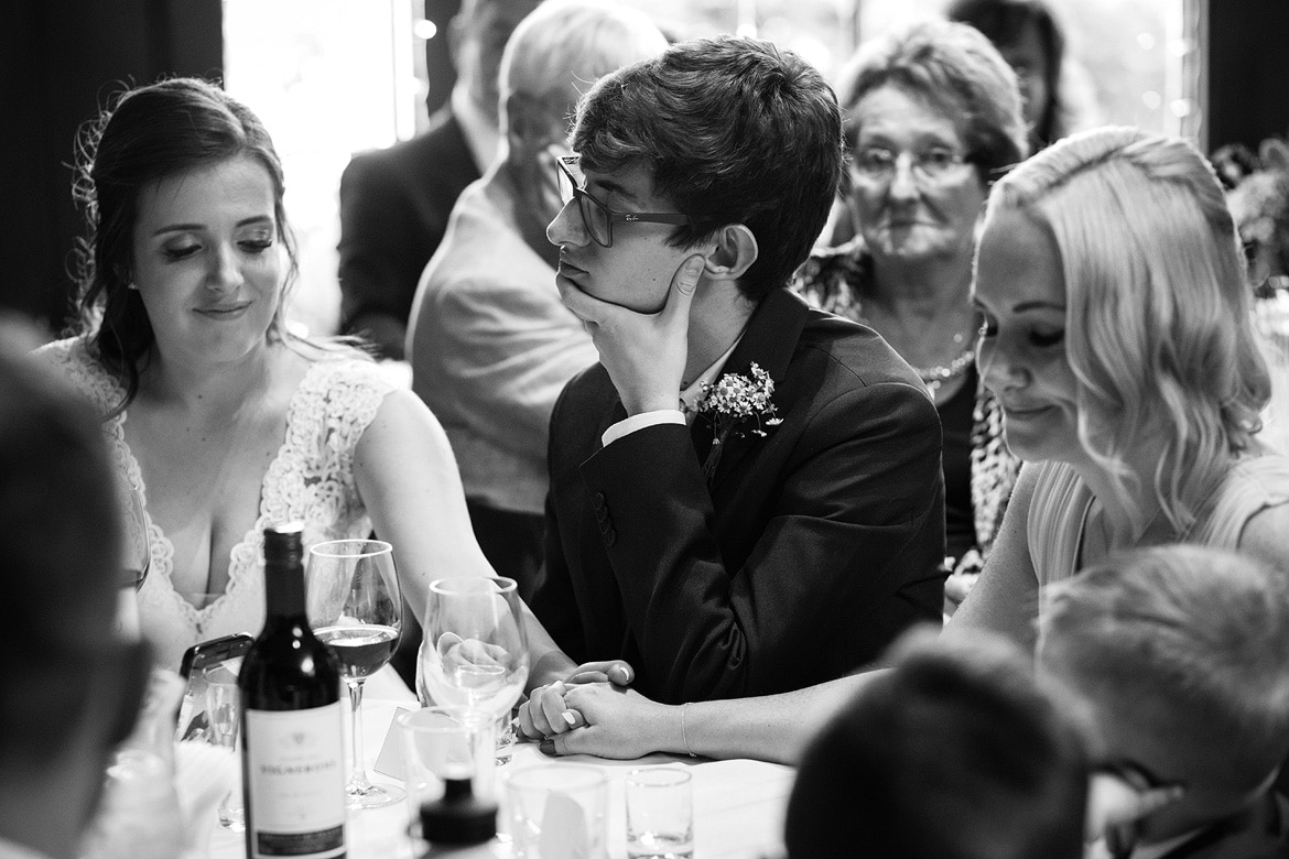 bride and her matron of honor hold hands during the wedding speeches