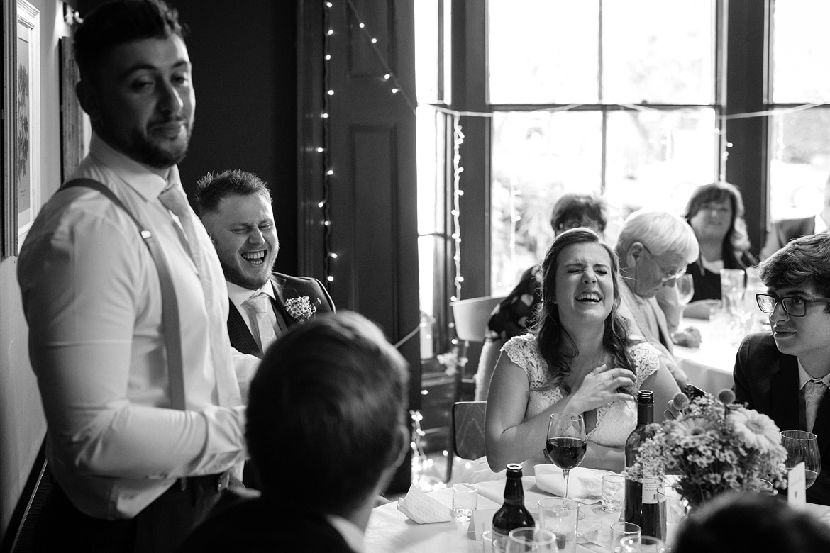 bride and groom laugh at the best mans speech