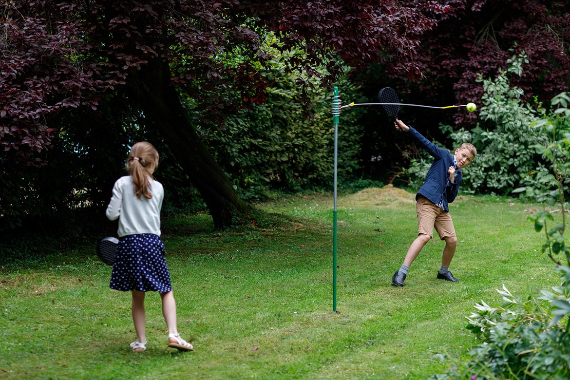 children play swingball in the garden