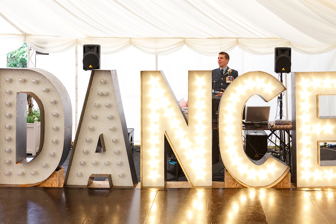 the groom stands behind his homemade lighting display