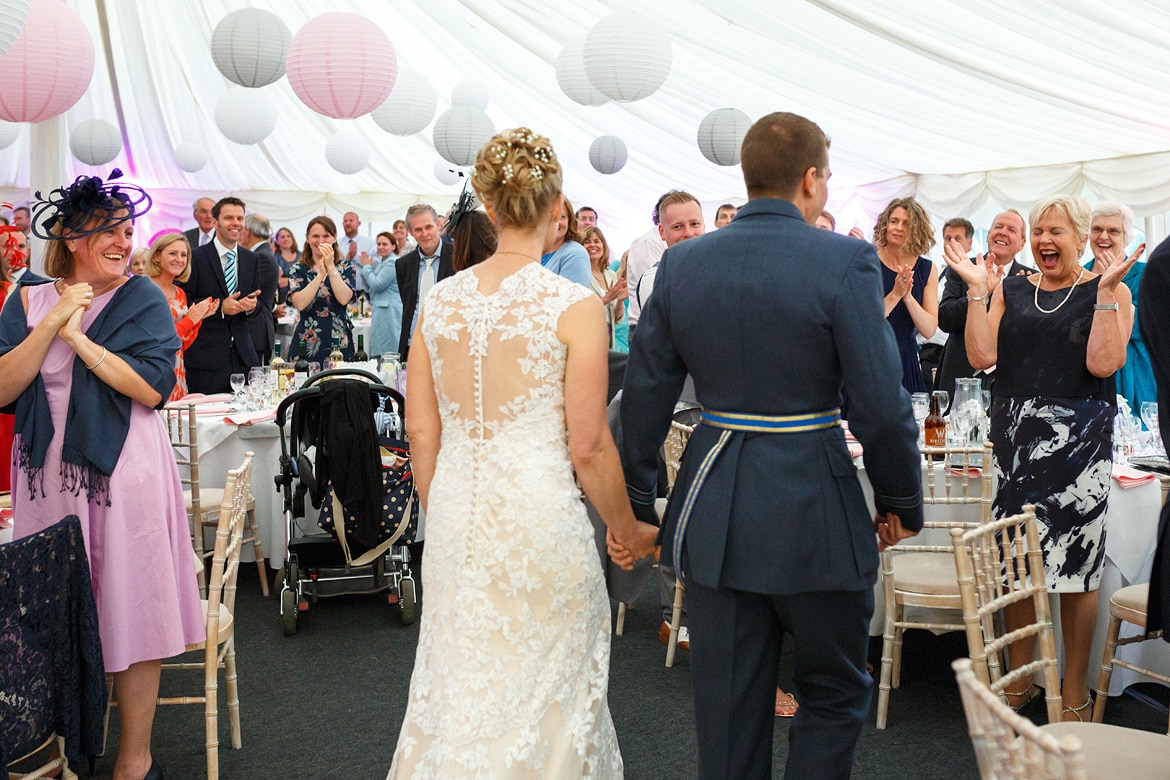 bride and groom enter the marquee for the wedding breakfast