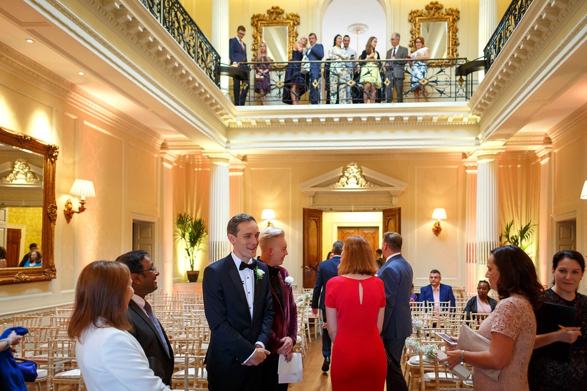 the groom greets wedding guests in the centre hall at hedsor house