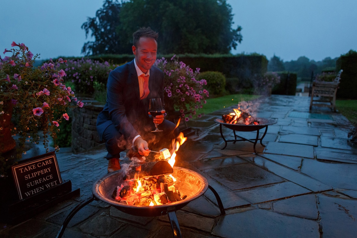 a wedding guest toasts marshmallows outside hedsor house