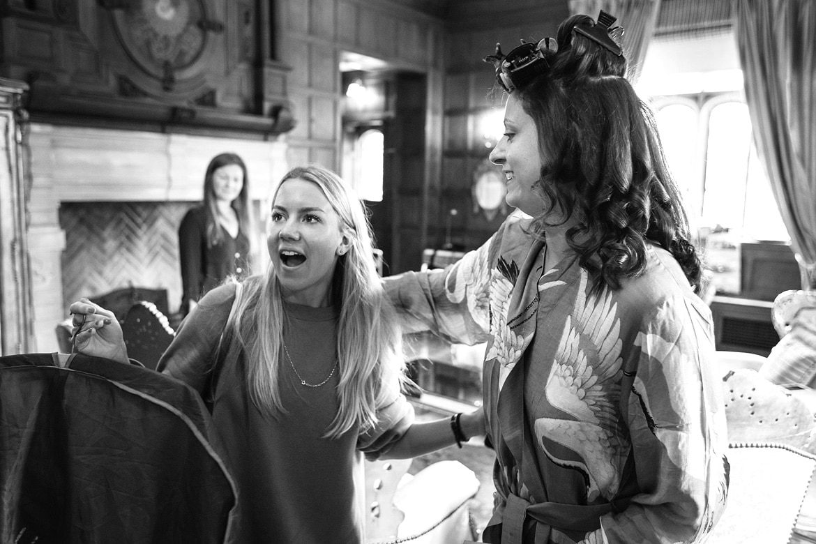 alice looks at her wedding dress with a bridesmaid