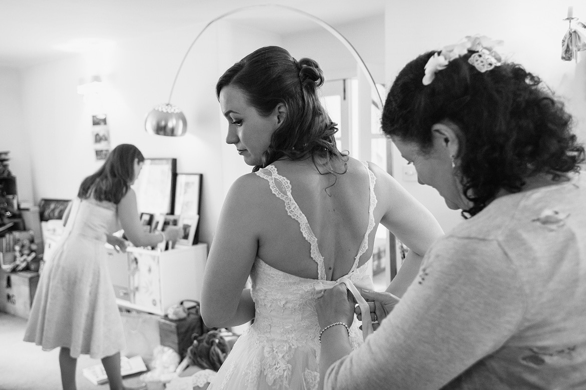 the brides mother helps her into her dress