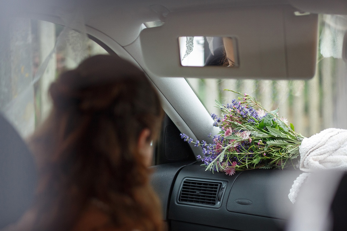 the brides bouquet on the dashboard of the wedding car