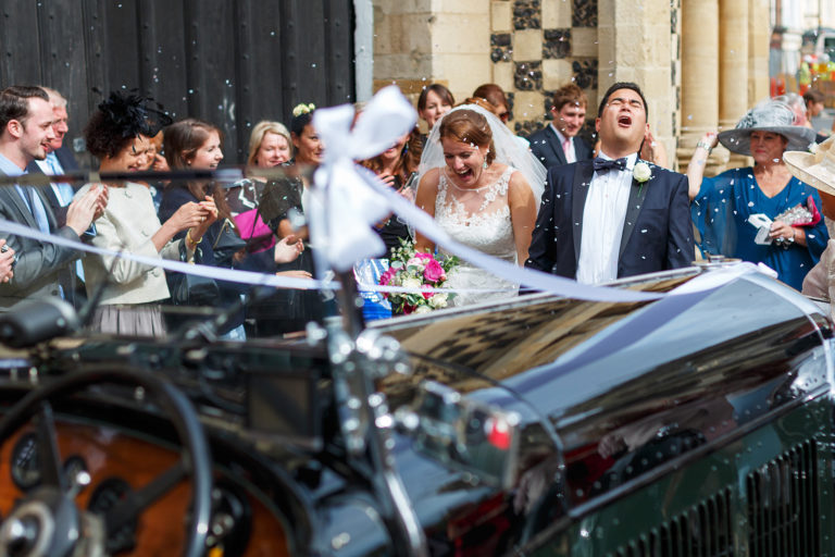 bride and groom walking through confetti after their kings lynn wedding ceremony