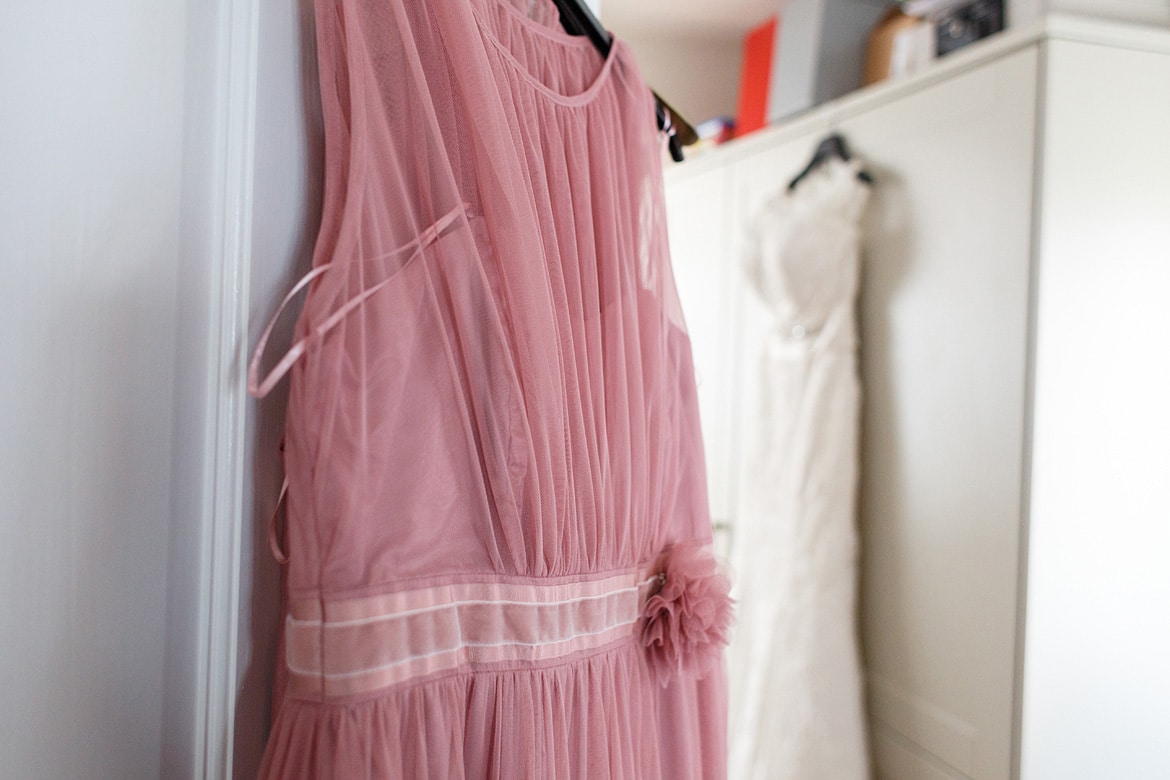 a bridesmaids dress hanging with the brides dress in the background