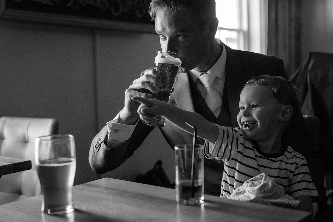 the groom takes a drink with his son on his lap