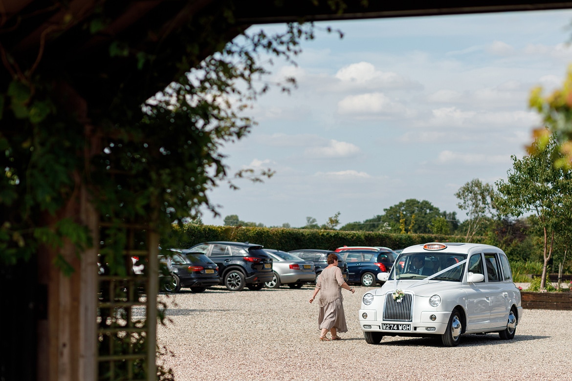 the bride arrives at maidens barn in a white london taxi