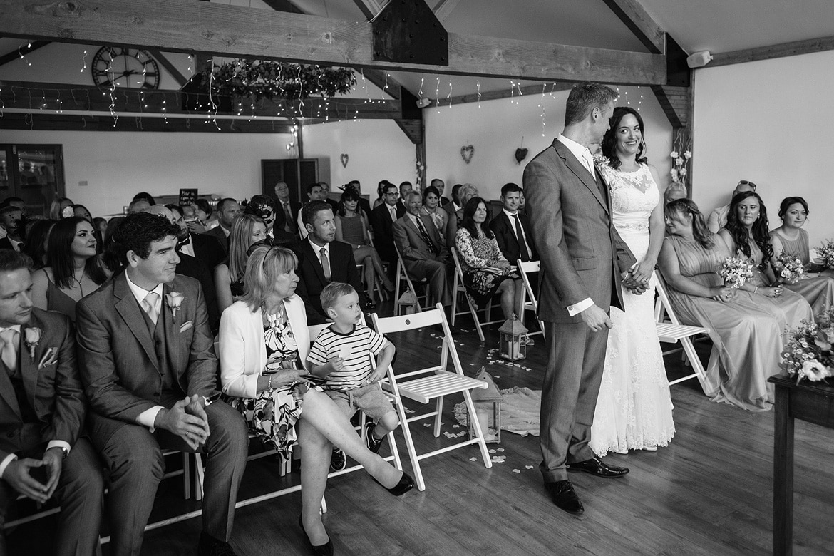 bride and groom peek nervously at each other during their maidens barn wedding ceremony