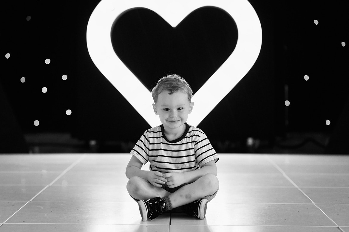 the bride and grooms son sitting in front of a love heart