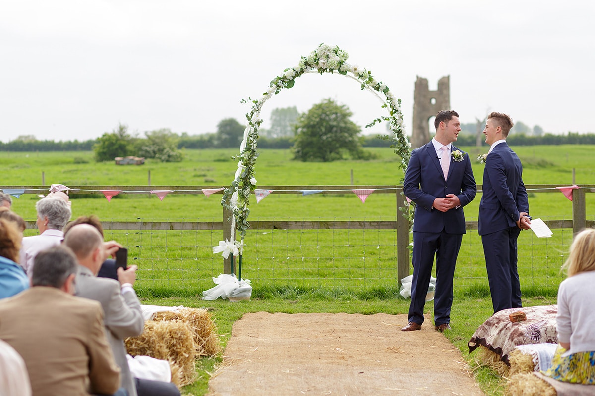 the groom waits with the godwick church ruin in the background