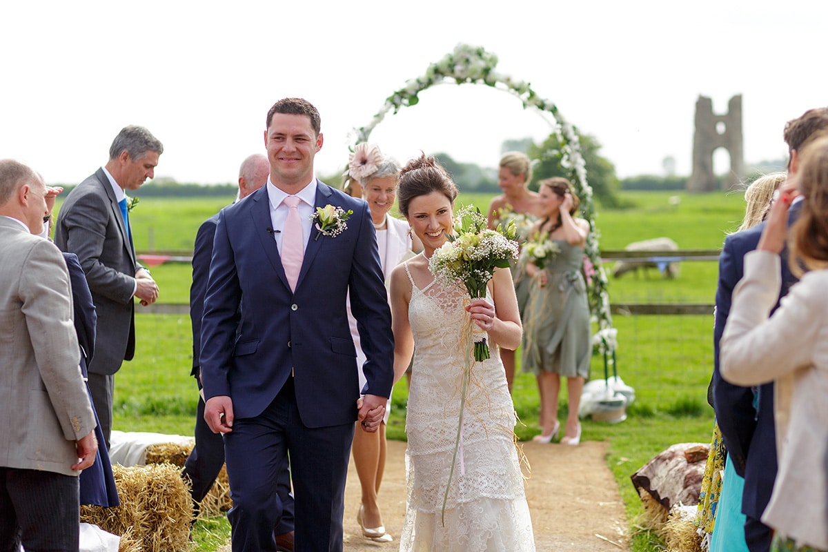 bride and groom walk smiling down the aisle