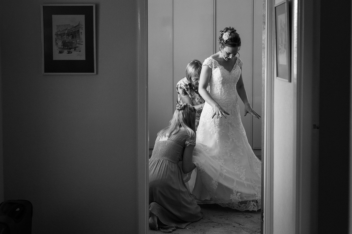 the bride puts her dress on in the bedroom