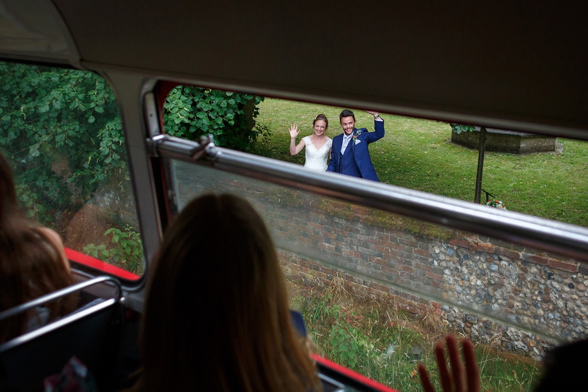 kate and daniel wave off their guests in the routemaster bus