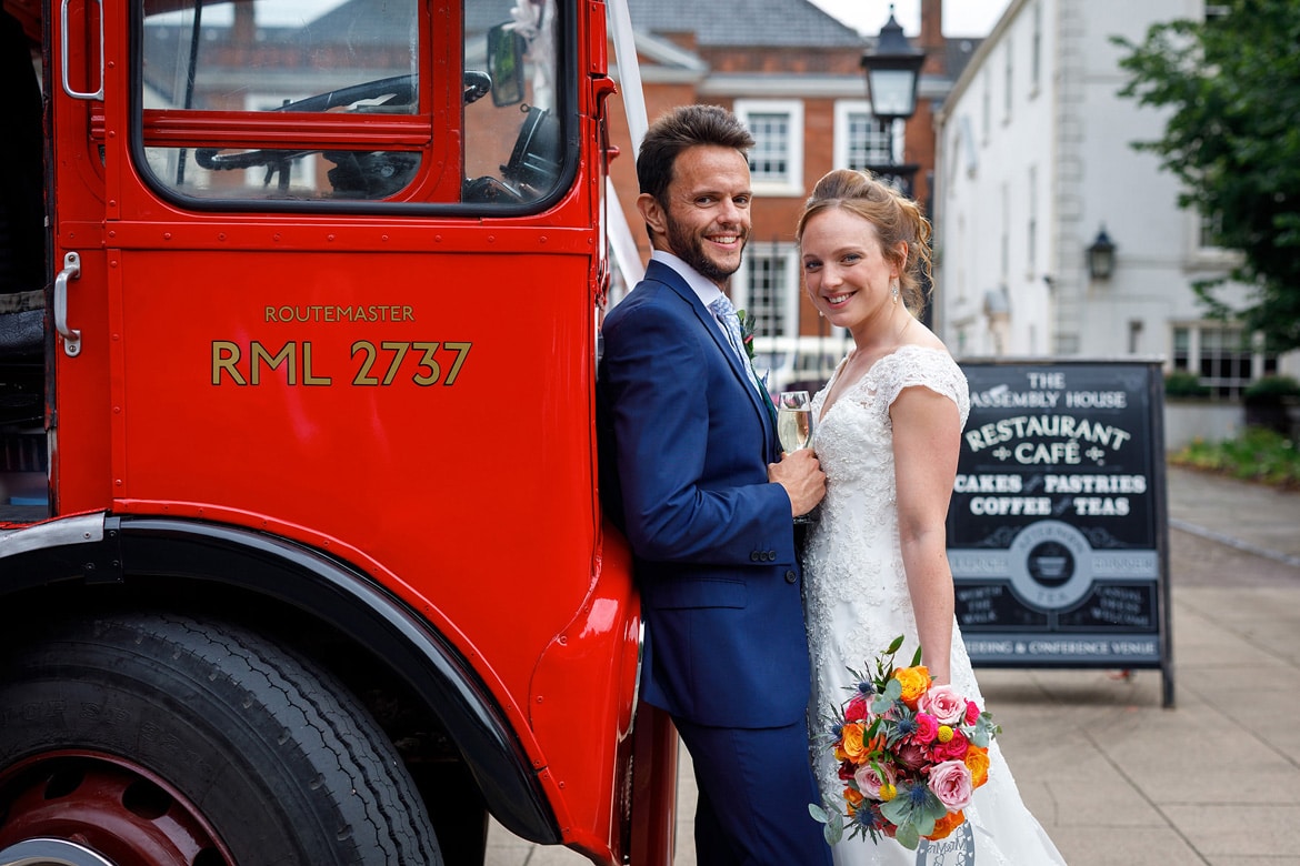 bride and groom pose with the routemaster bus outside the assembly house norwich