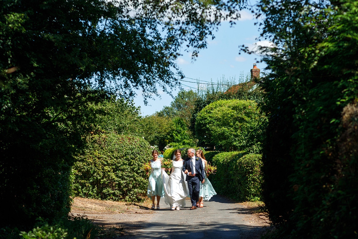 the bride and her father walk to old buckenham church