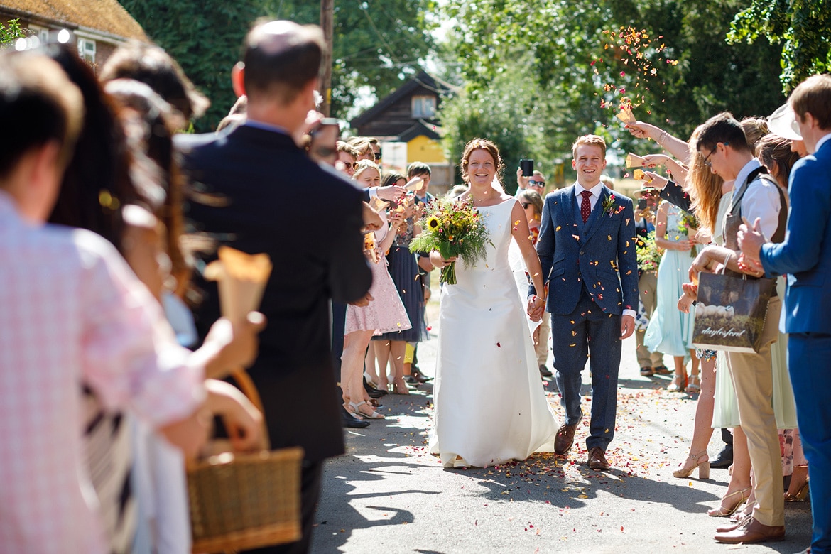 bride and groom walk through the confetti at their summer wedding