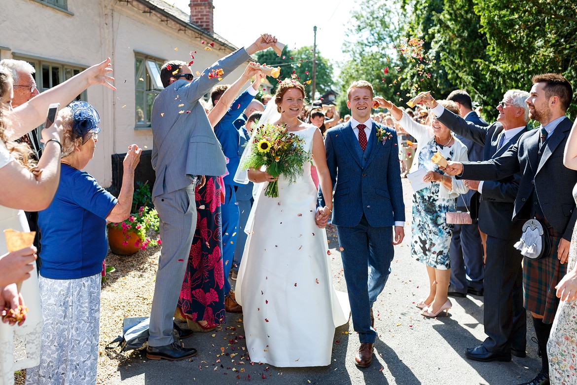 bride and groom walk through the confetti at their old buckenham wedding