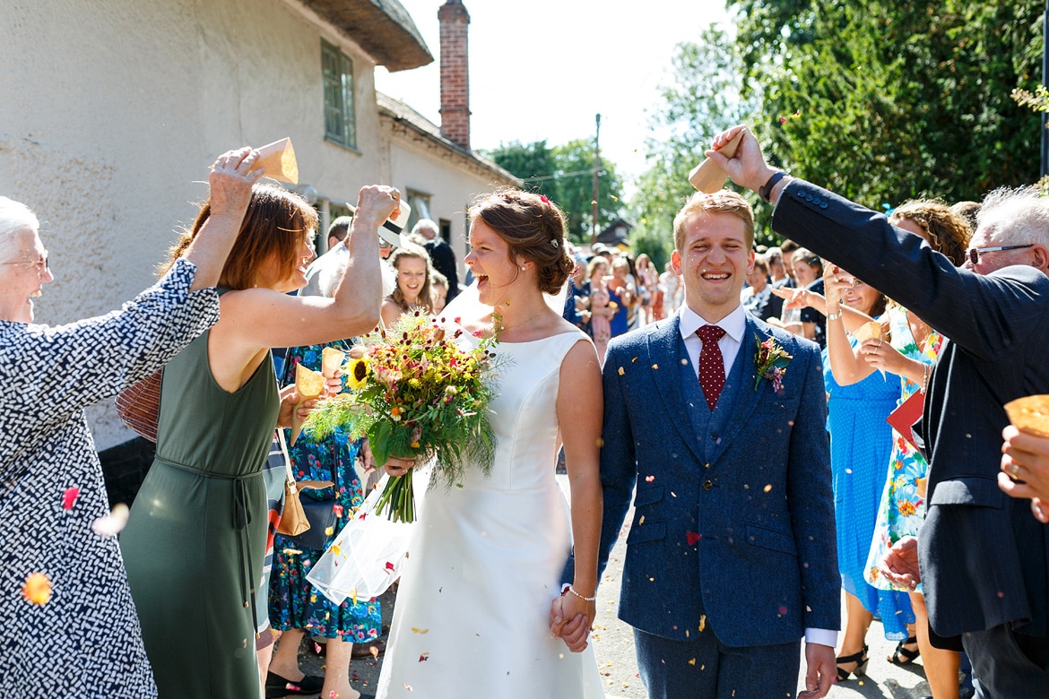 bride and groom walk through the confetti at their summer wedding