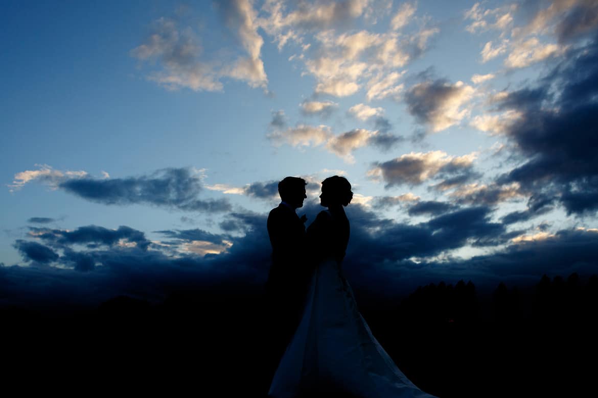 the bride and groom silhouetted against the sunset