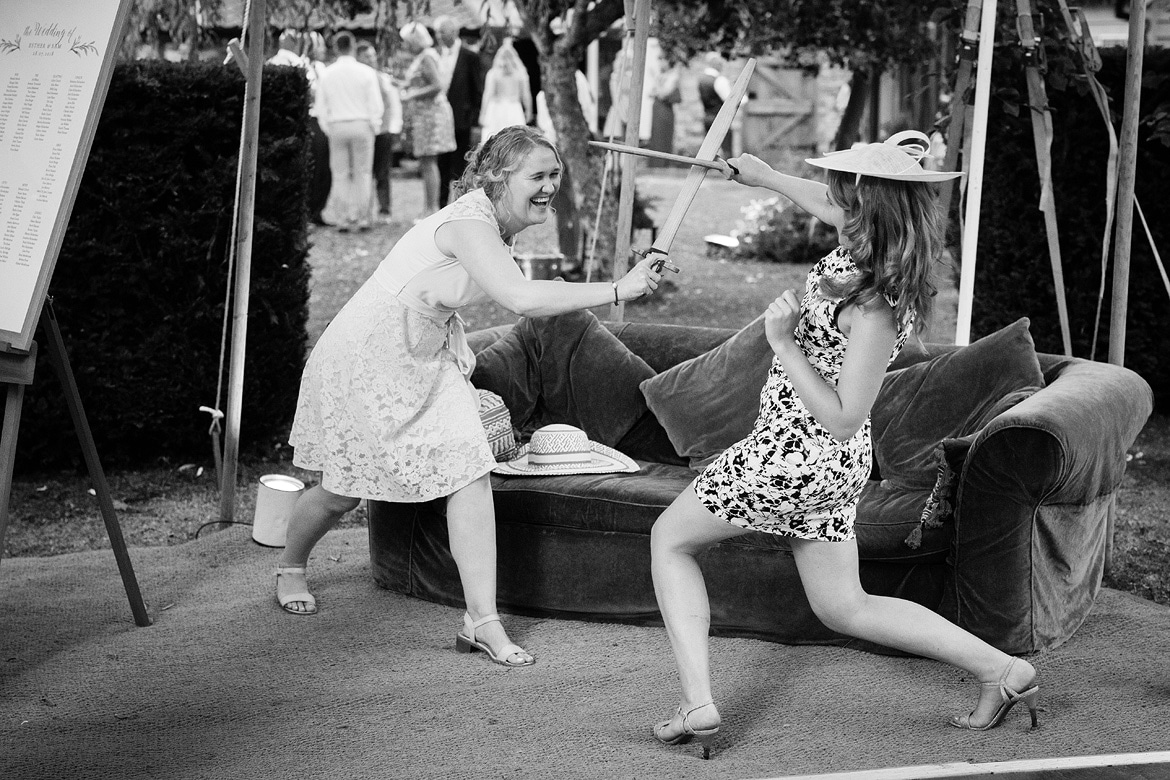 two wedding guests play fighting with swords