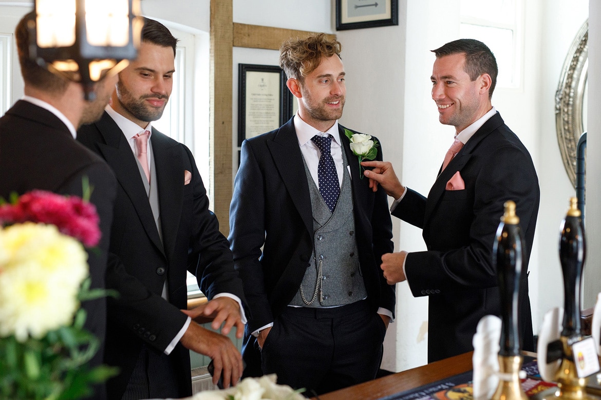 an usher pins on the grooms buttonhole