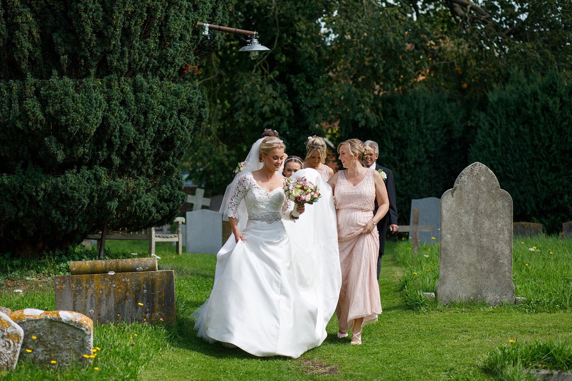 bride and bridesmaids walk through the churchyard