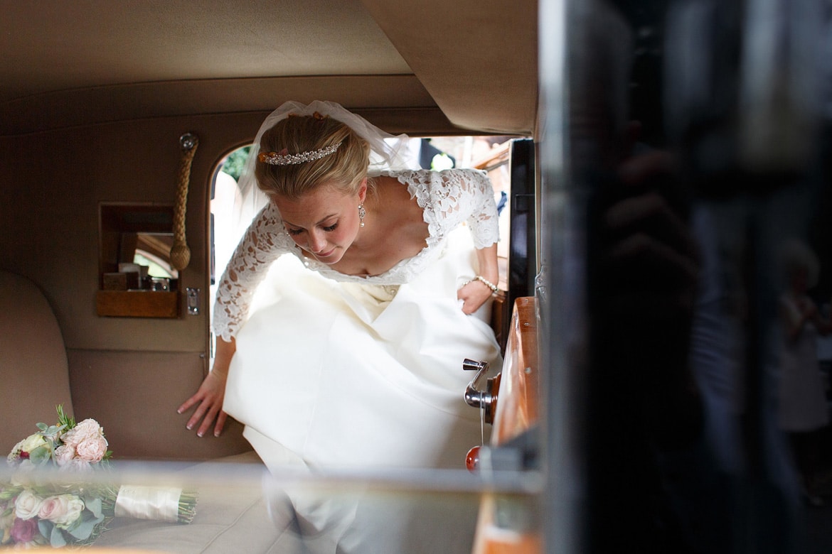 the bride gets into the wedding car