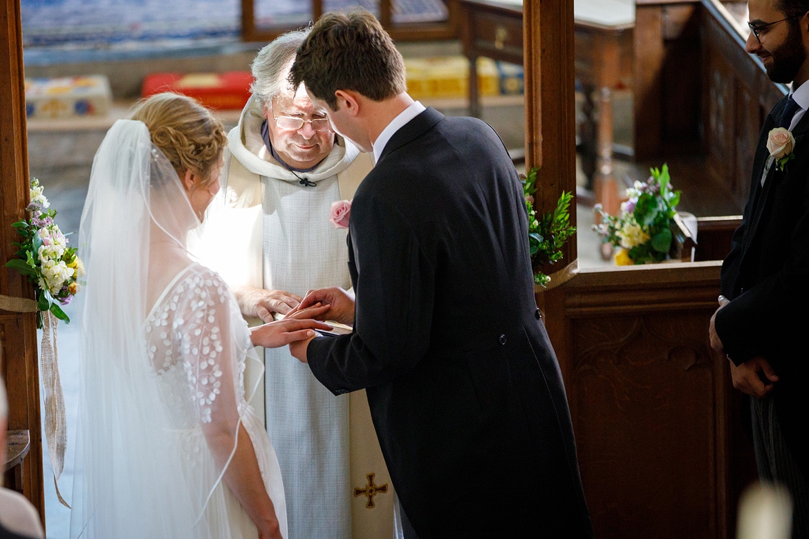 the groom places the brides ring on her finger