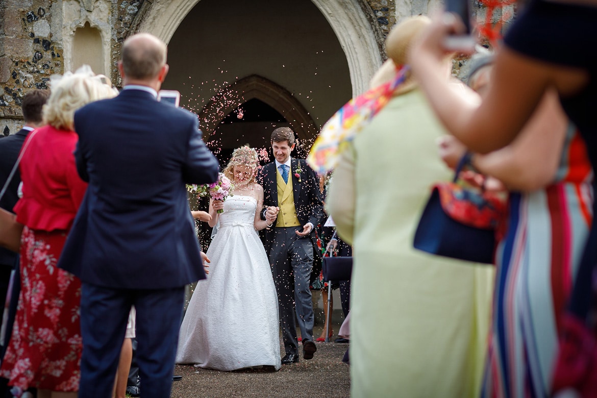 bride and groom walk through the confetti