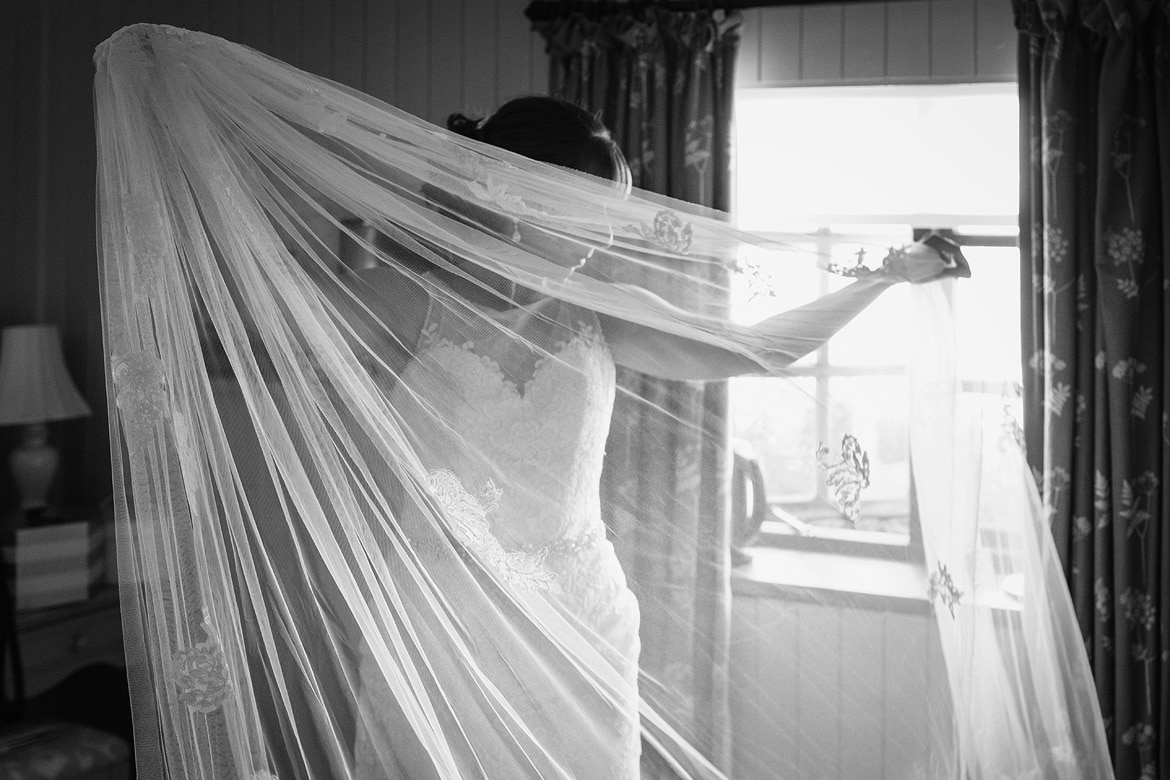 a bride preparing her veil at a cley mill wedding