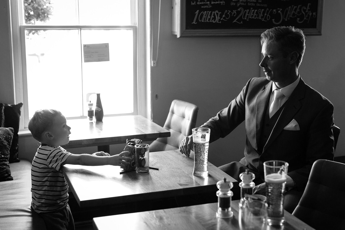 the groom and his son enjoy a drink before the wedding ceremony