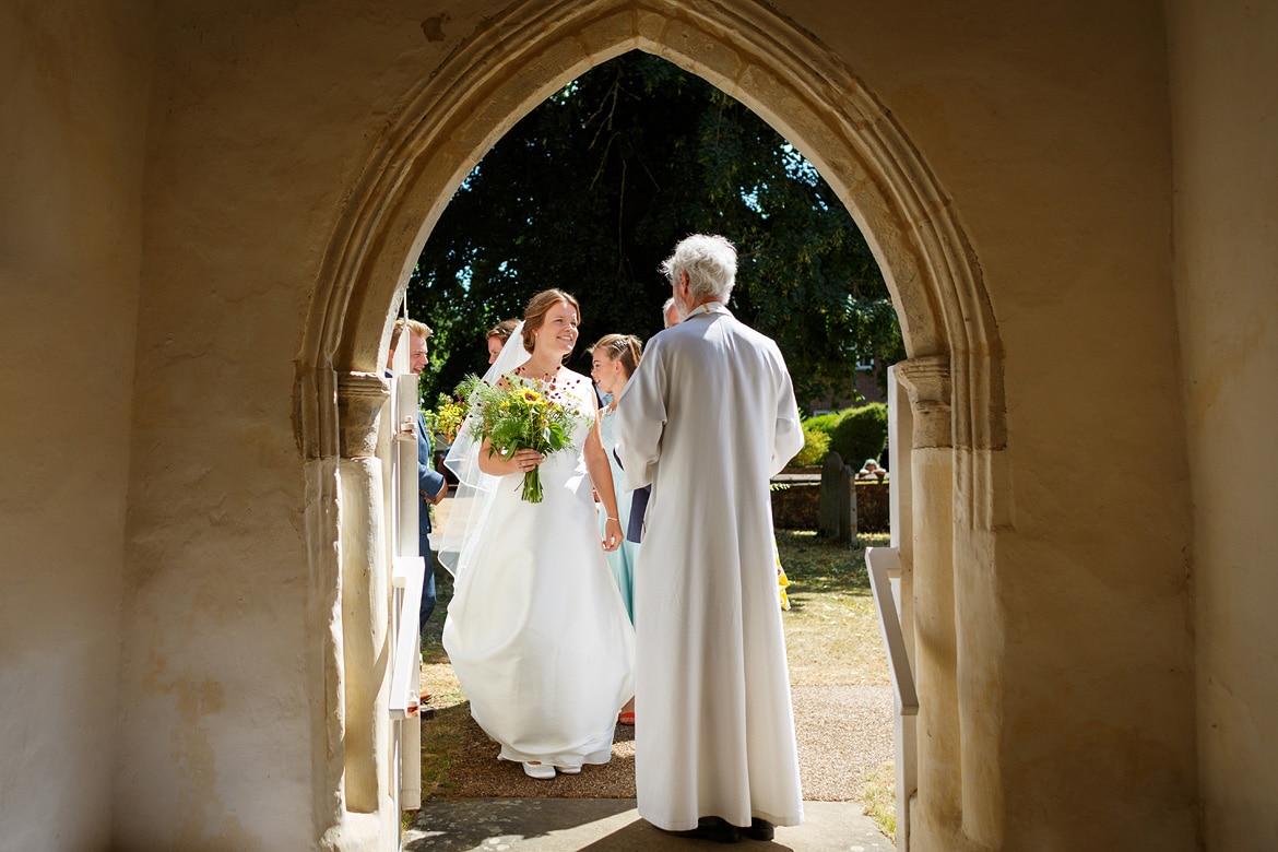a bride arrives at old buckenham church