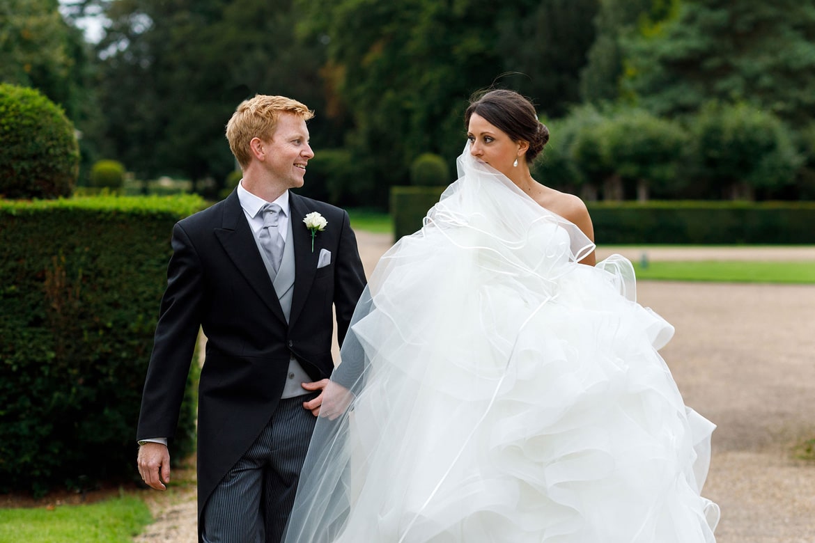 a bride peeks over her veil at hengrave hall