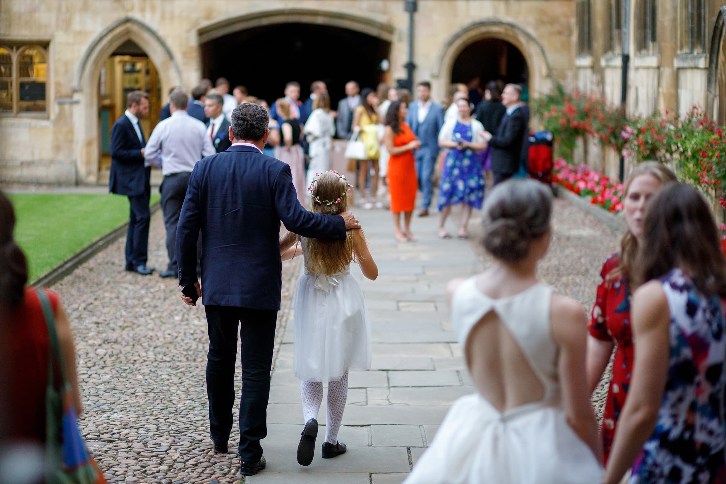 a bridesmaid walks with her father through pembroke college