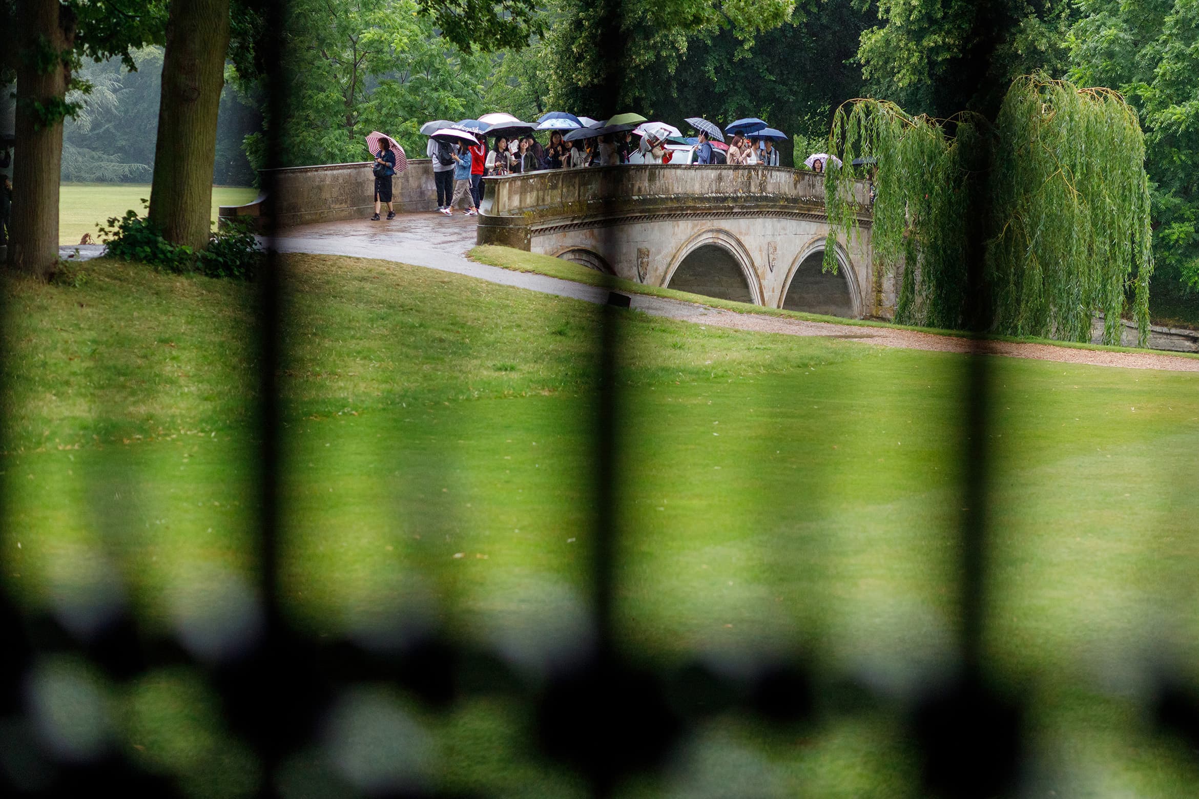 tourists walking over trinity college bridge 