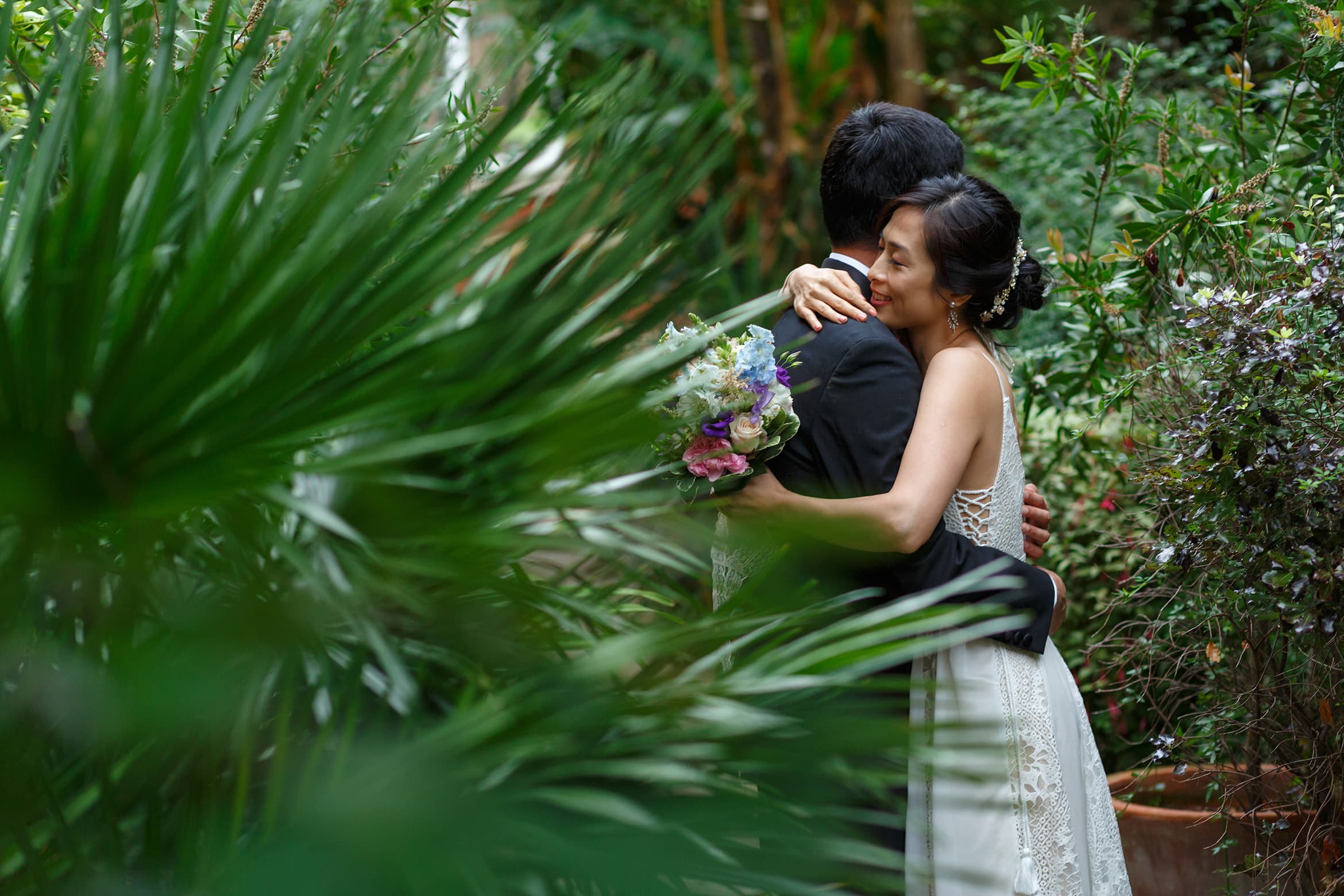 bride and groom hug in the grounds of trinity college